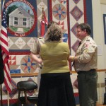 Mom pins the Eagle Badge to his uniform